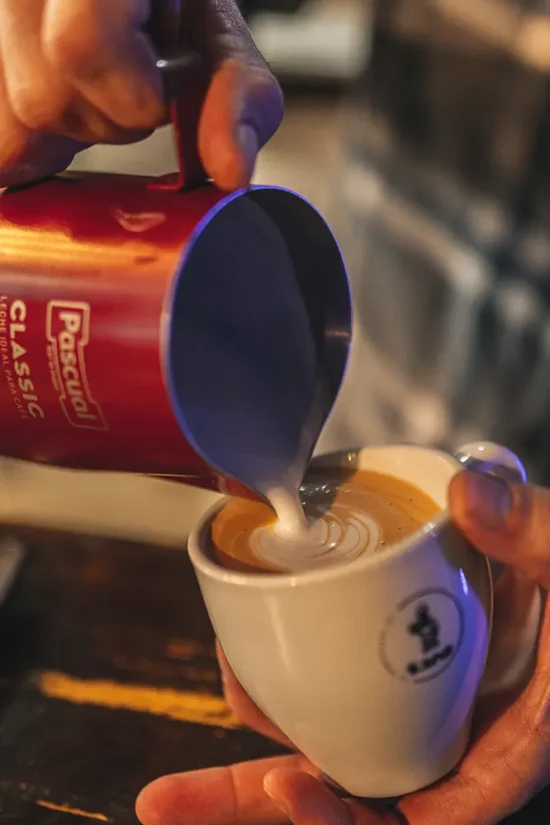 Barista sirviendo un café con leche y realizando dibujo con espuma en cafeteria tano gandia